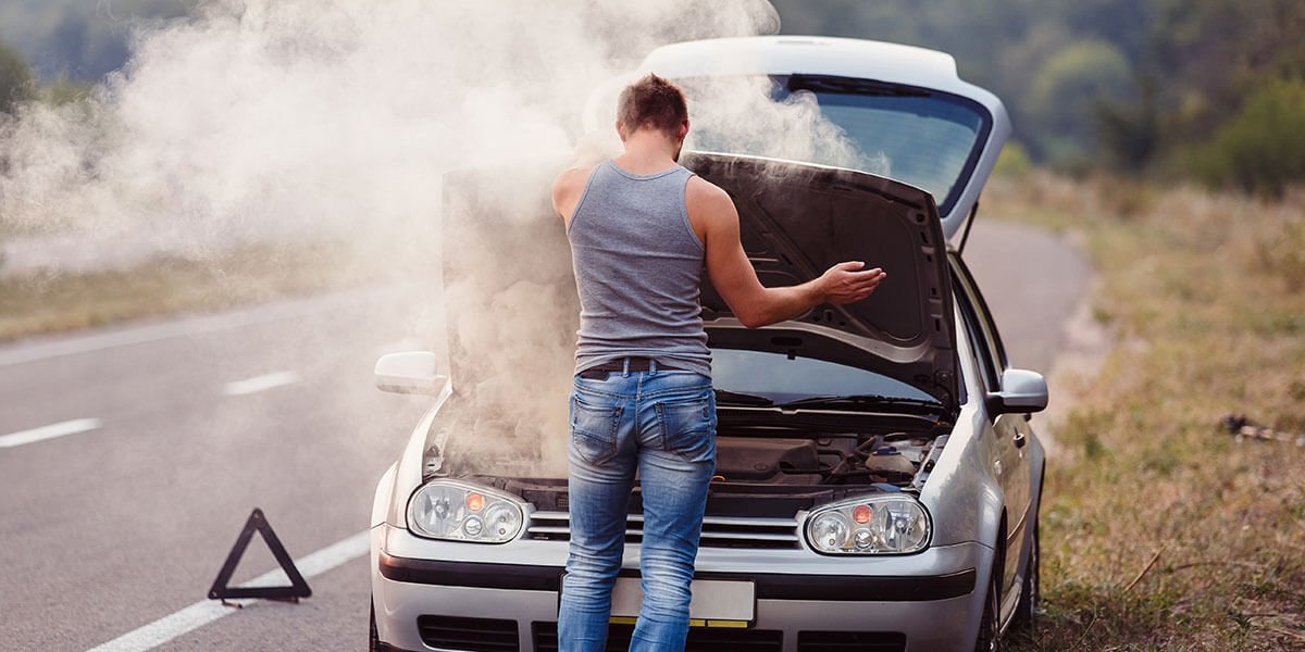 Florida Lemon Law concept shows a man at the side of the road looking at smoke rising from the engine of a car with its hood open